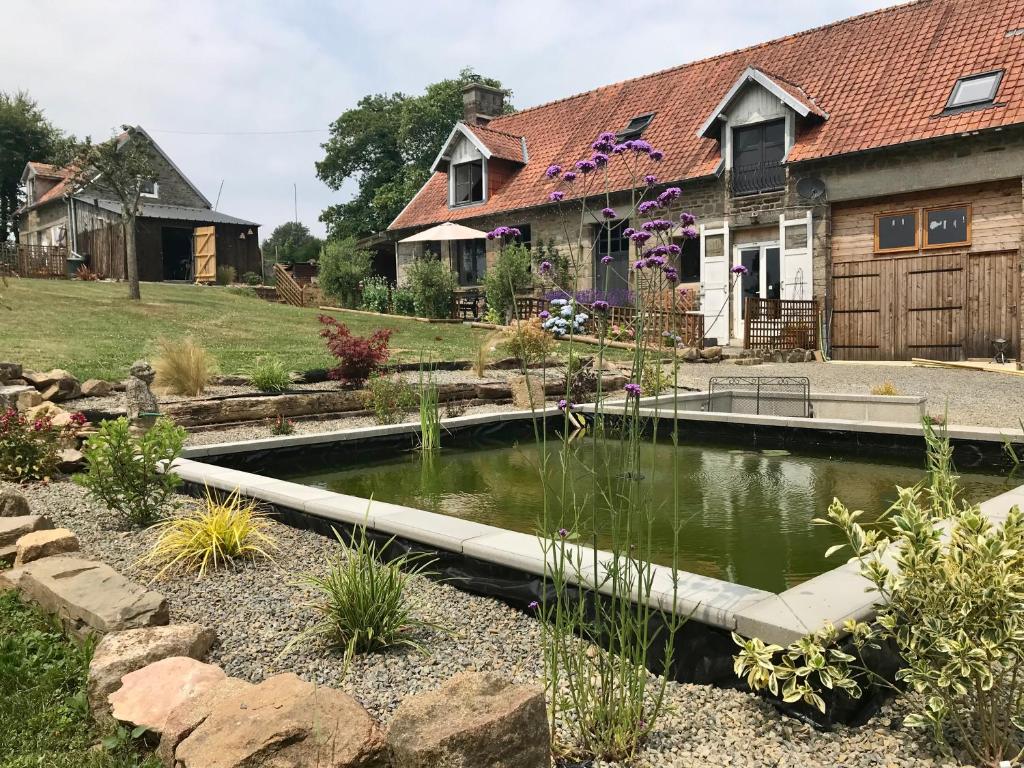 einen Garten mit einem Teich vor einem Haus in der Unterkunft Ferme de Noyes in Sourdeval
