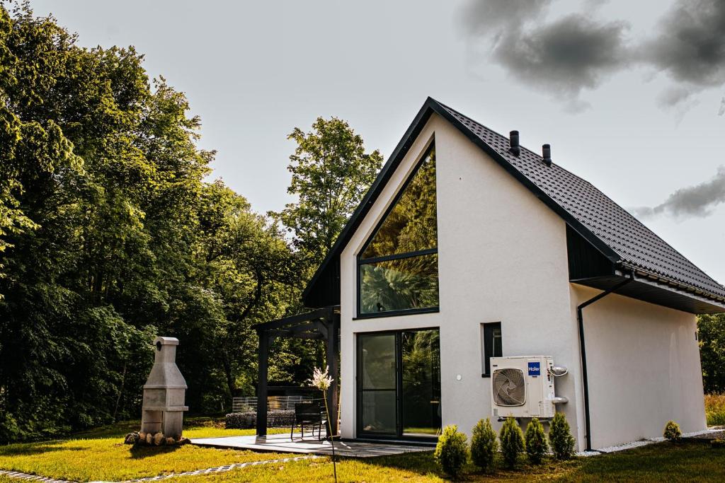a small white house with a black roof at Domki Nad Starym Potokiem in Ustrzyki Dolne