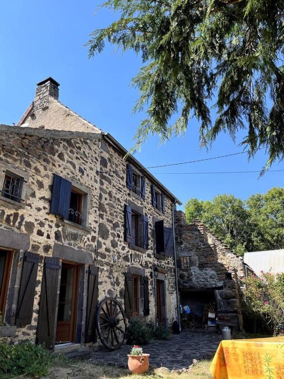 une ancienne maison en pierre avec une roue devant elle dans l'établissement Maison auvergnate, à Dauzat-sur-Vodable