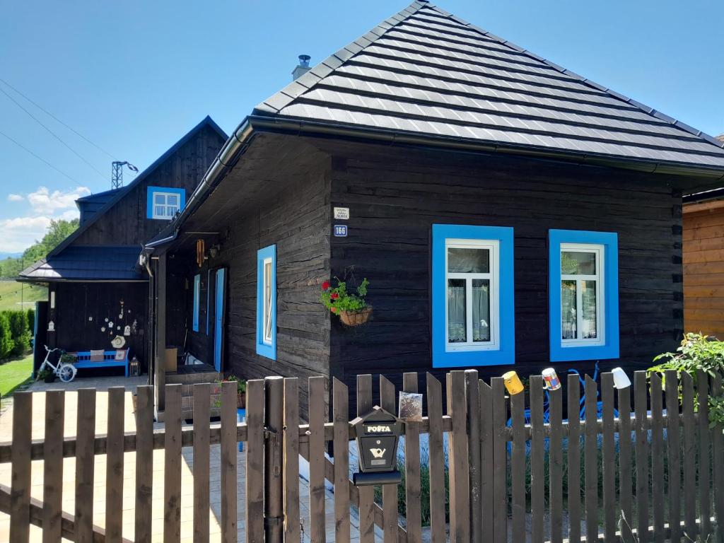 a black house with blue windows and a fence at Drevenica Liptovsky Trnovec 166 in Liptovský Trnovec