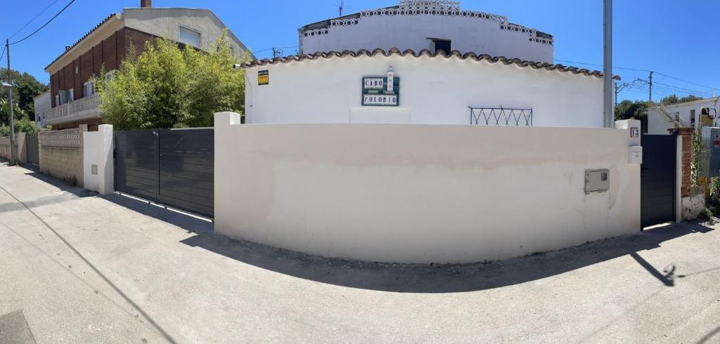 een wit gebouw met een hek naast een straat bij Apartamento Cabo Polonio in Tarragona