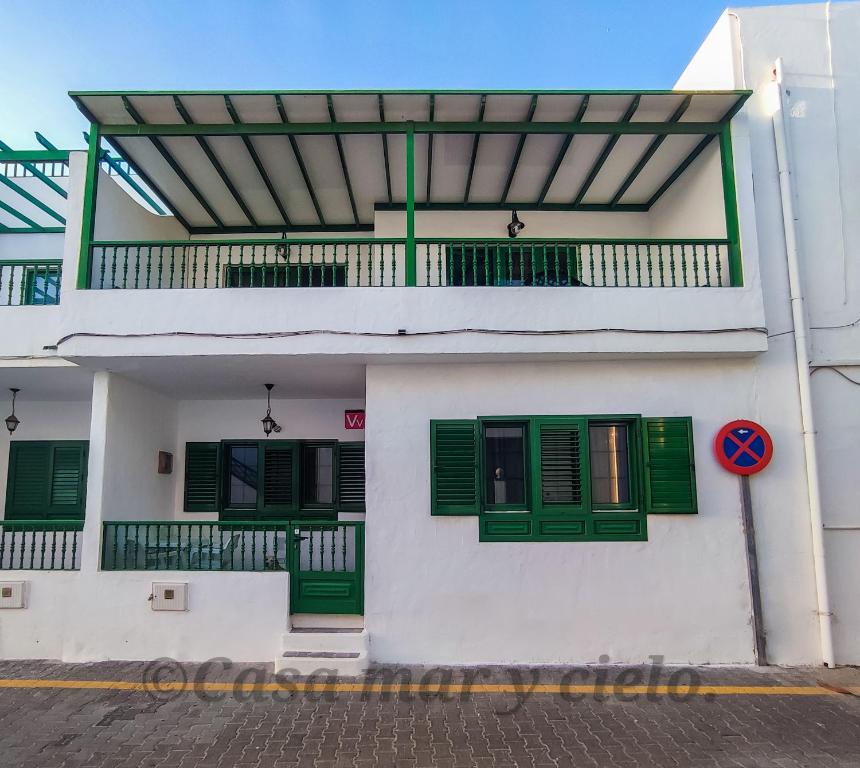 a white building with green windows and a balcony at Casa mar y cielo in Playa Blanca