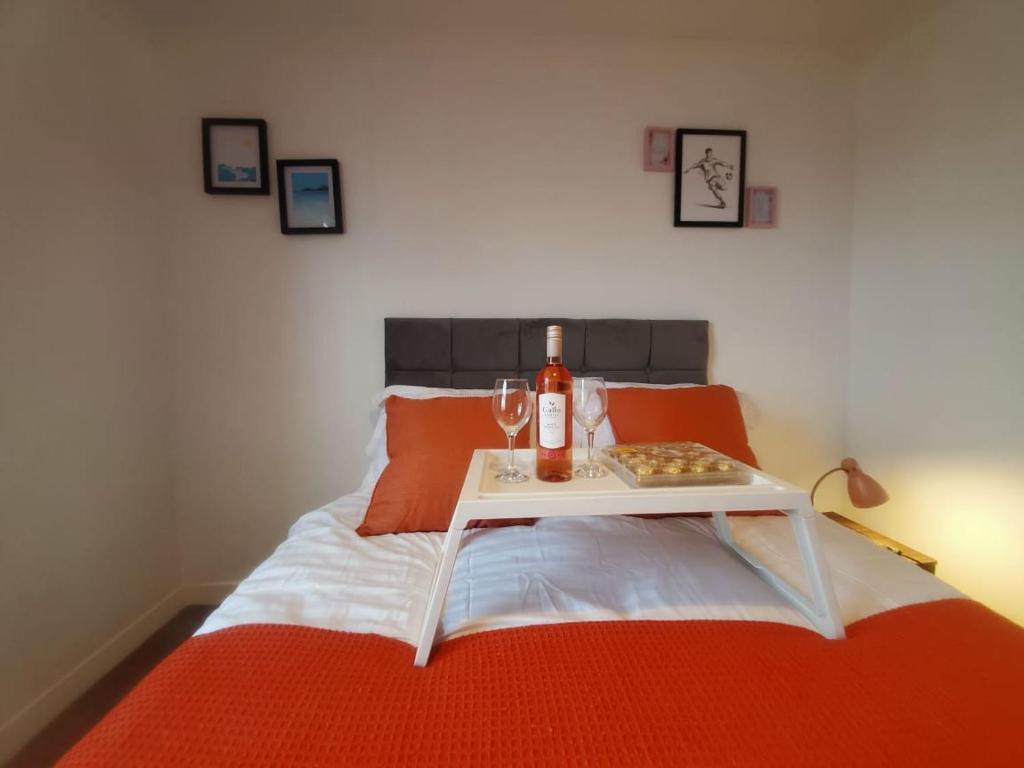 Una cama con una mesa con una botella de vino. en Aqua Suite en Gillingham