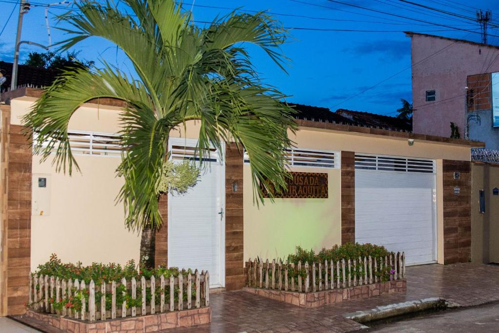 a palm tree in front of a house at Pousada Muiraquitã Parintins in Parintins