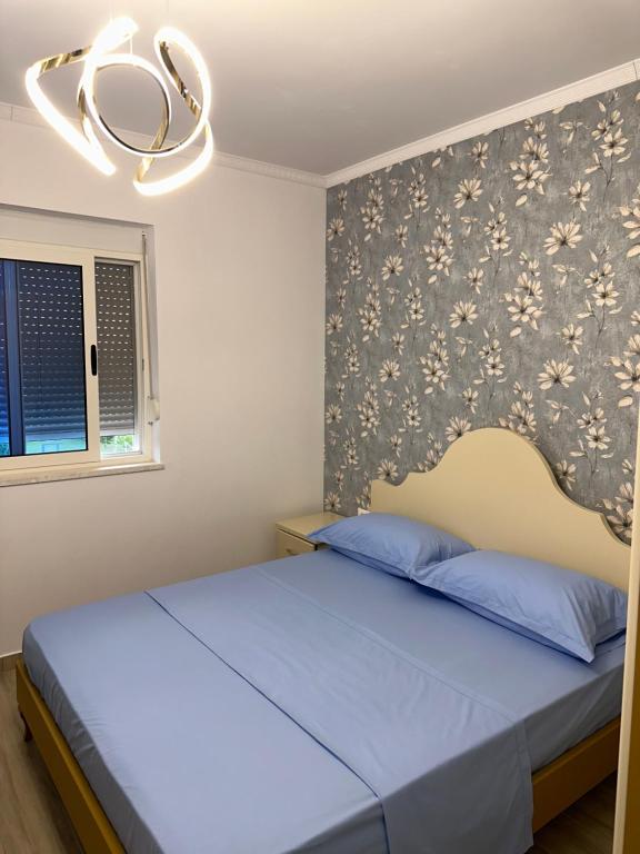a bedroom with a blue bed with a floral wallpaper at Casa de la Playa in Shkodër