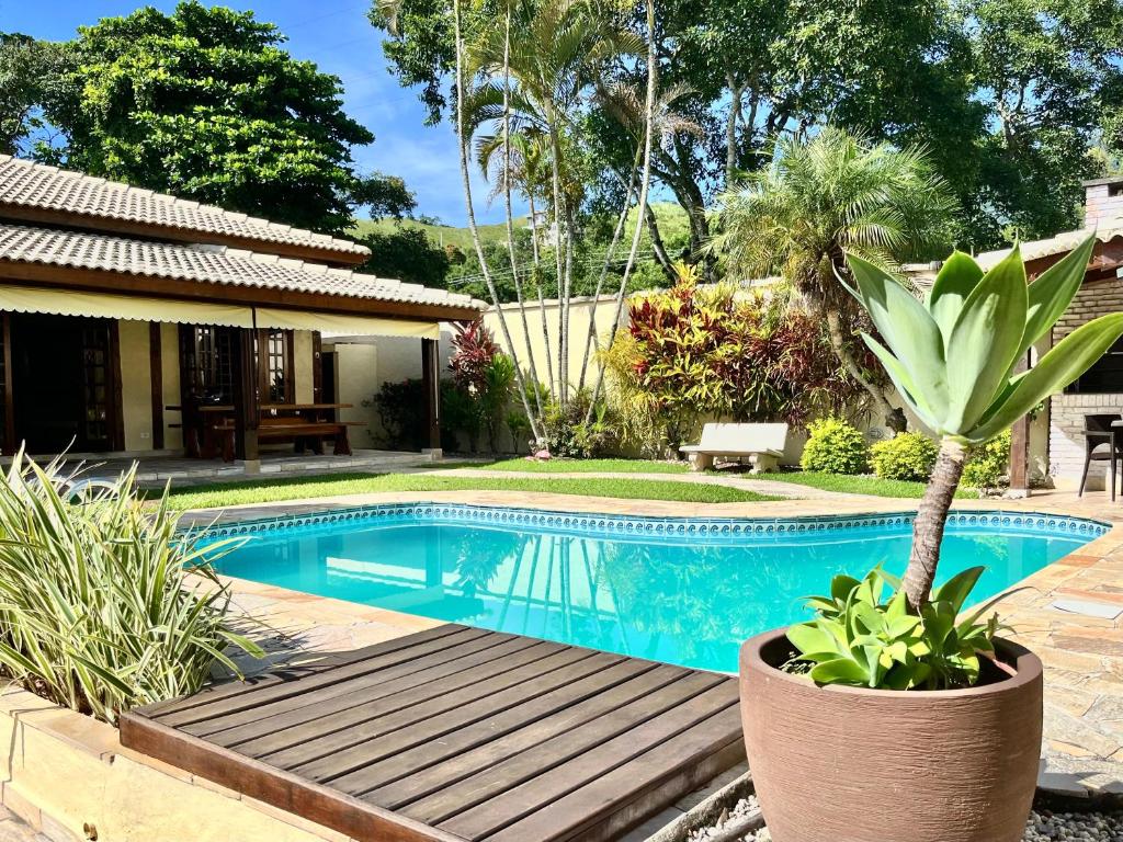 a swimming pool in a garden with a palm tree at Casa de temporada estilo rústico - Litoral Norte de SP in São Sebastião