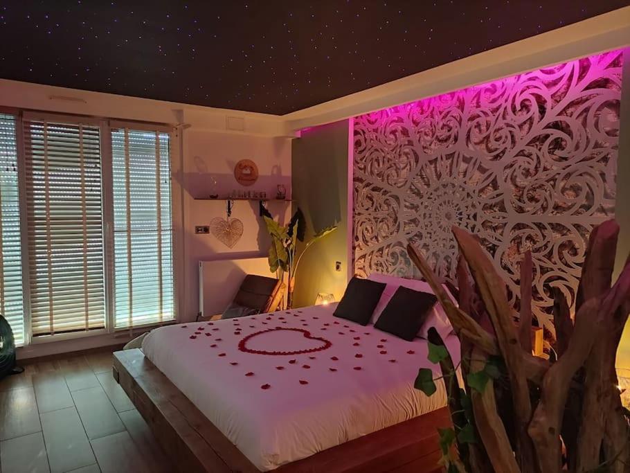 - une chambre avec un grand lit et un éclairage rose dans l'établissement Cocon d'Evasion**** SPA PRIVATIF et ciels étoilés, au Havre