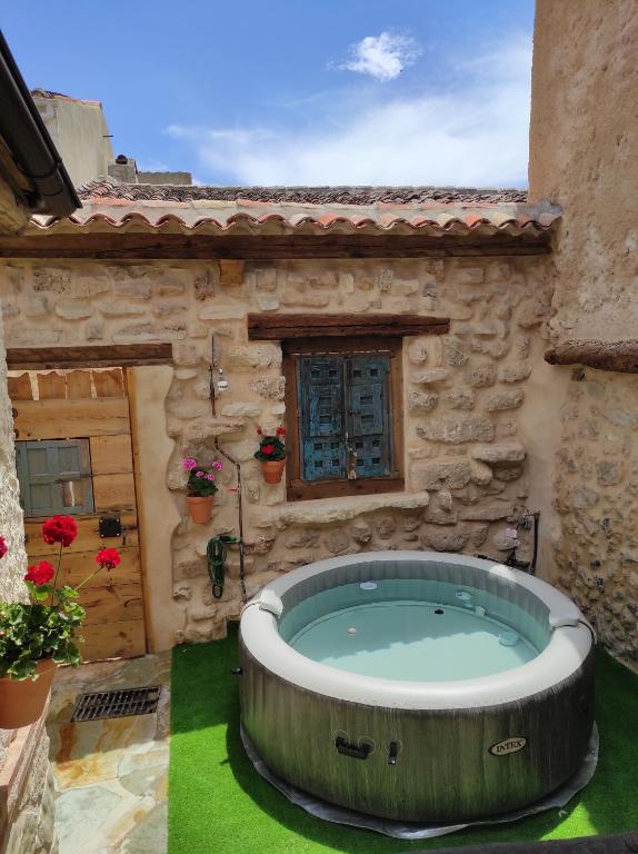 an outdoor hot tub in the yard of a stone building at Casa rural El Rincón de las Estrellas in Sigüenza