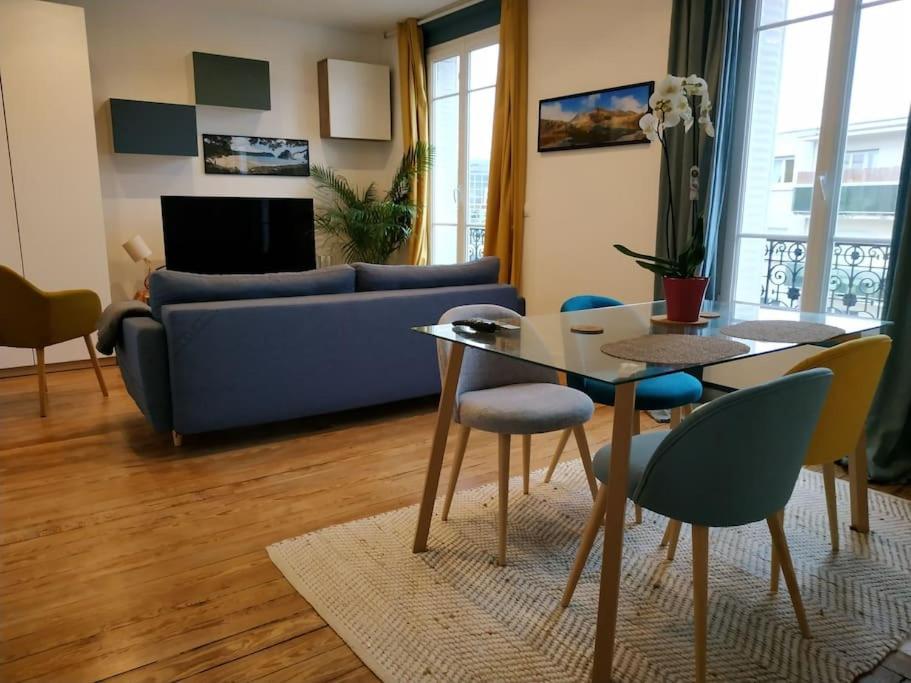 een woonkamer met een tafel en een blauwe bank bij Superbe appartement moderne et lumineux à Puteaux! in Puteaux