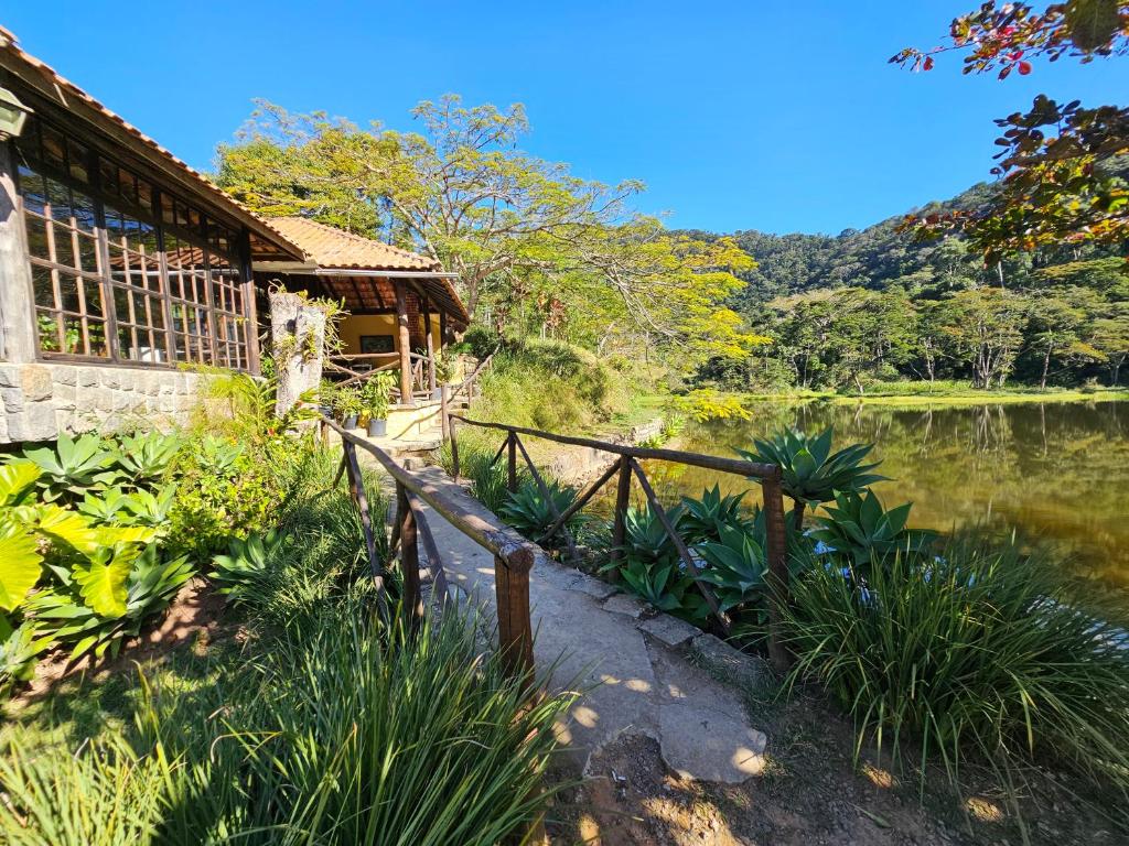 a house with a fence next to a lake at Hotel Fazenda Santo Antônio in Vassouras