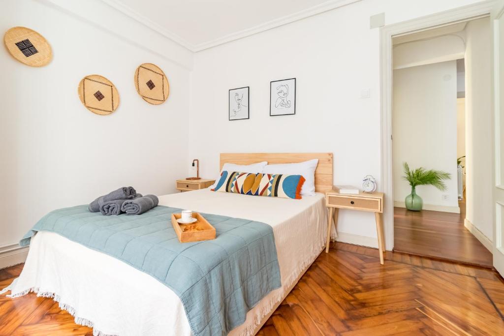 a white bedroom with a bed and a wooden floor at Moderno apartamento en pleno centro in Santander