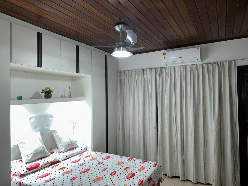 a bedroom with a bed and a ceiling fan at Quarto particular na praia do flamengo in Salvador