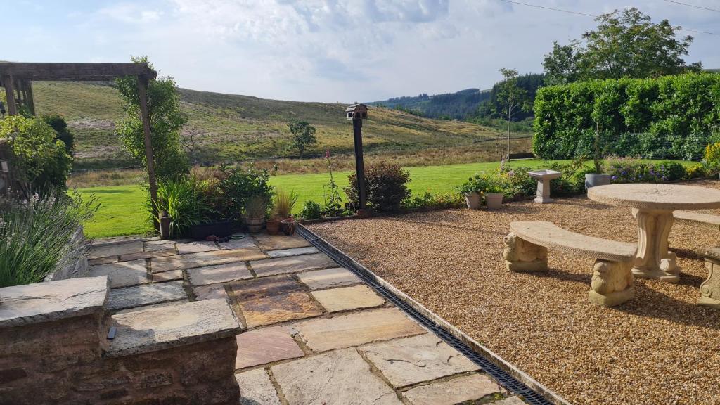 a stone patio with a table and a bench at Cadshaw Country Views in Darwen