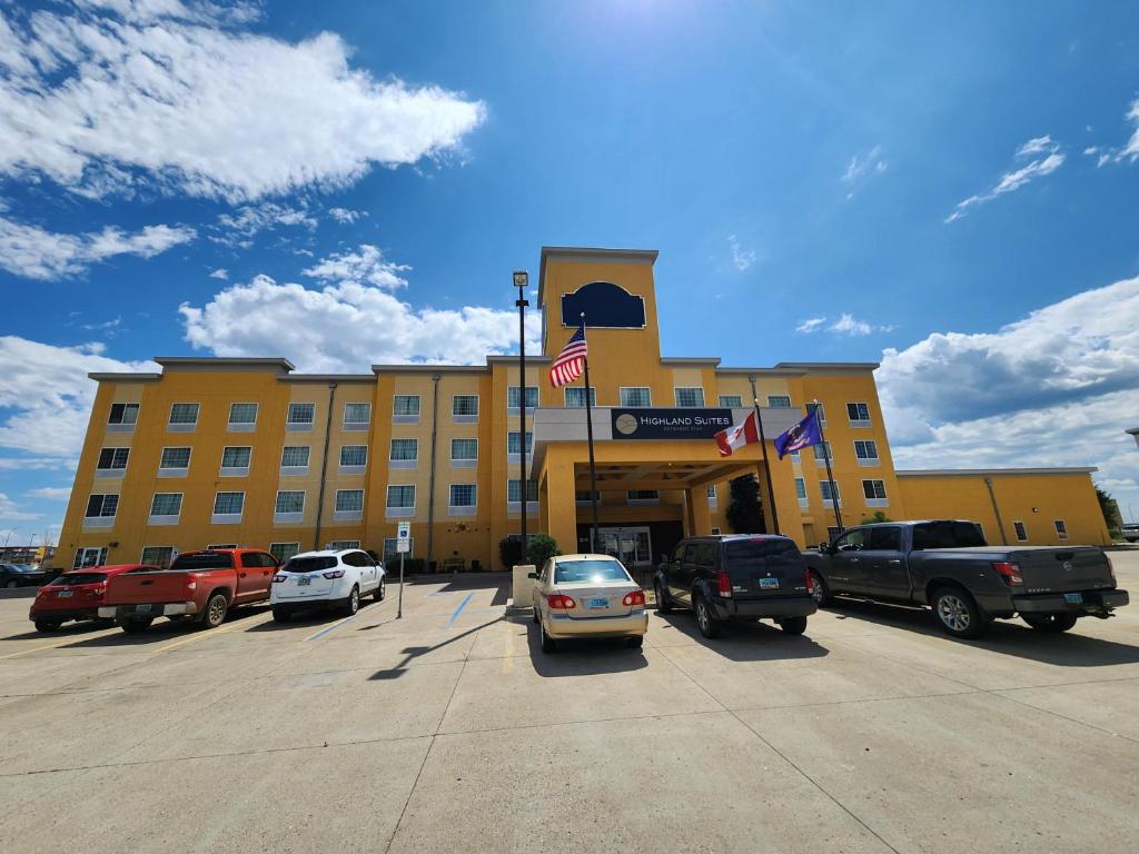 un edificio amarillo con coches estacionados en un estacionamiento en Highland Suites Extended Stay, en Minot