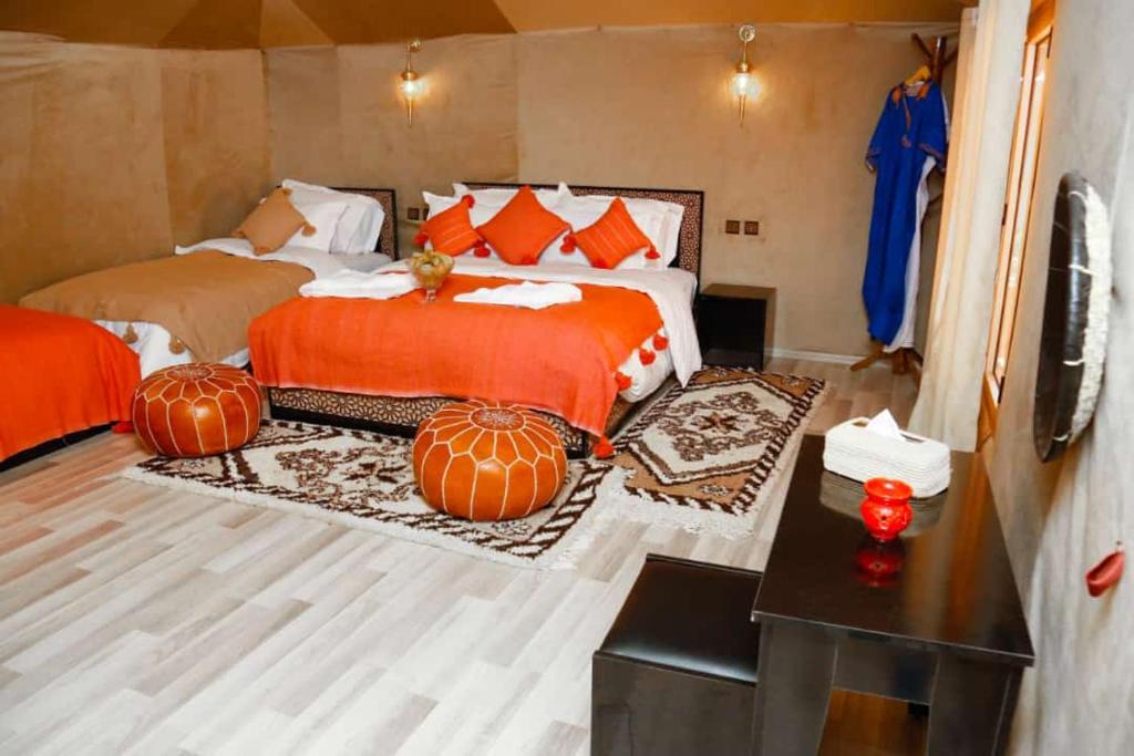 梅尔祖卡Desert Magic Camp的卧室配有两张床和南瓜,位于地板上
