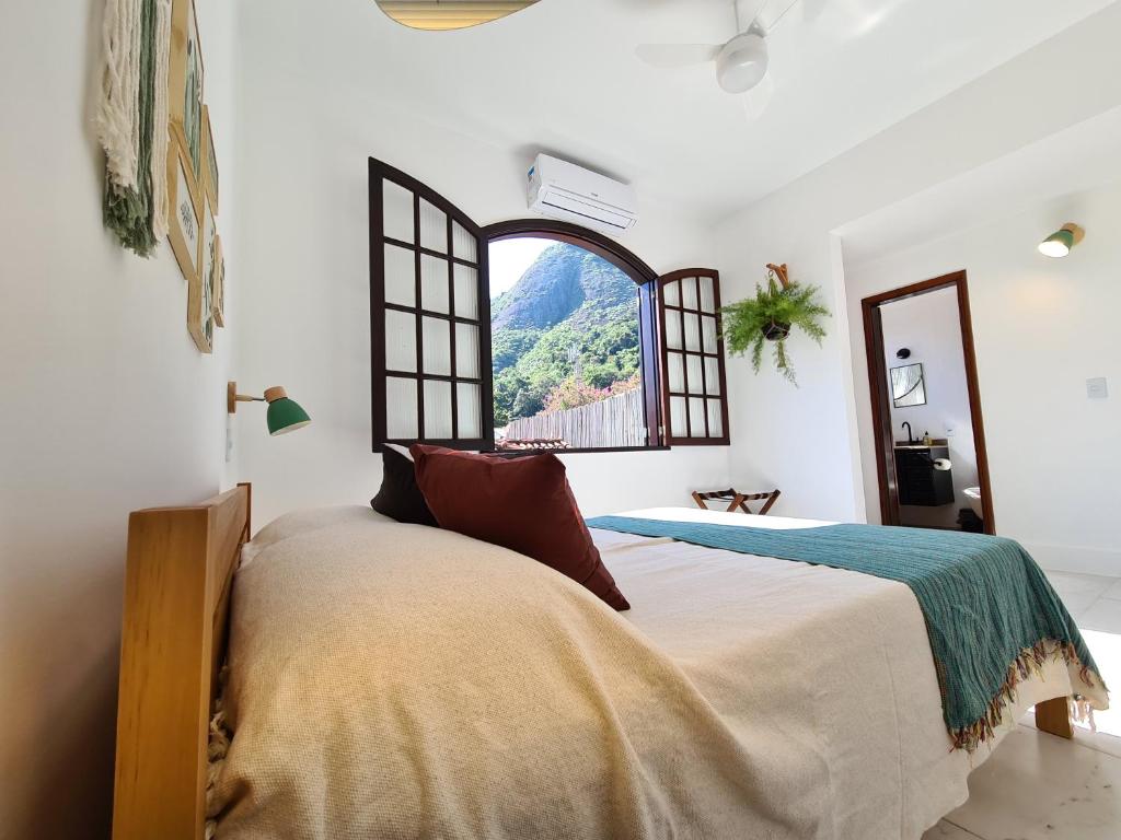 a bedroom with a large bed and a window at Itacoatiara - Apartamento com café da manhã ao lado da praia in Niterói