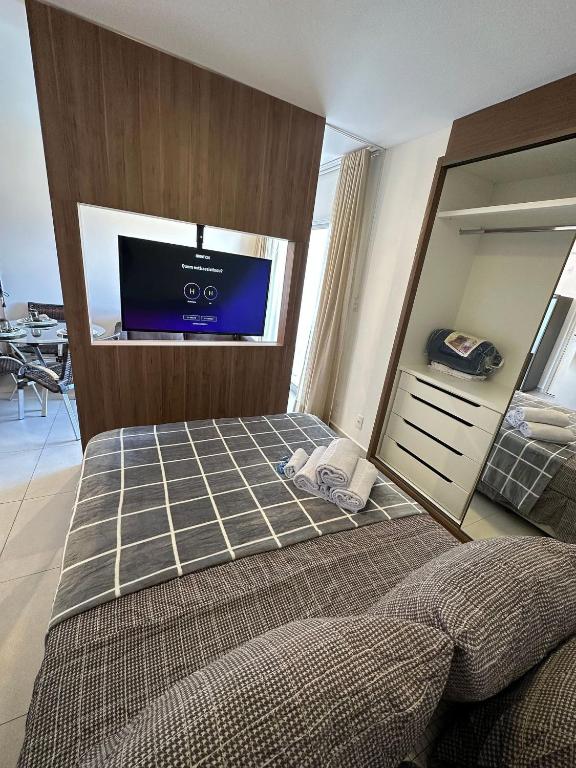 a bedroom with a bed and a flat screen tv at Studio Be Happy! piscina academia coz completa in Juiz de Fora