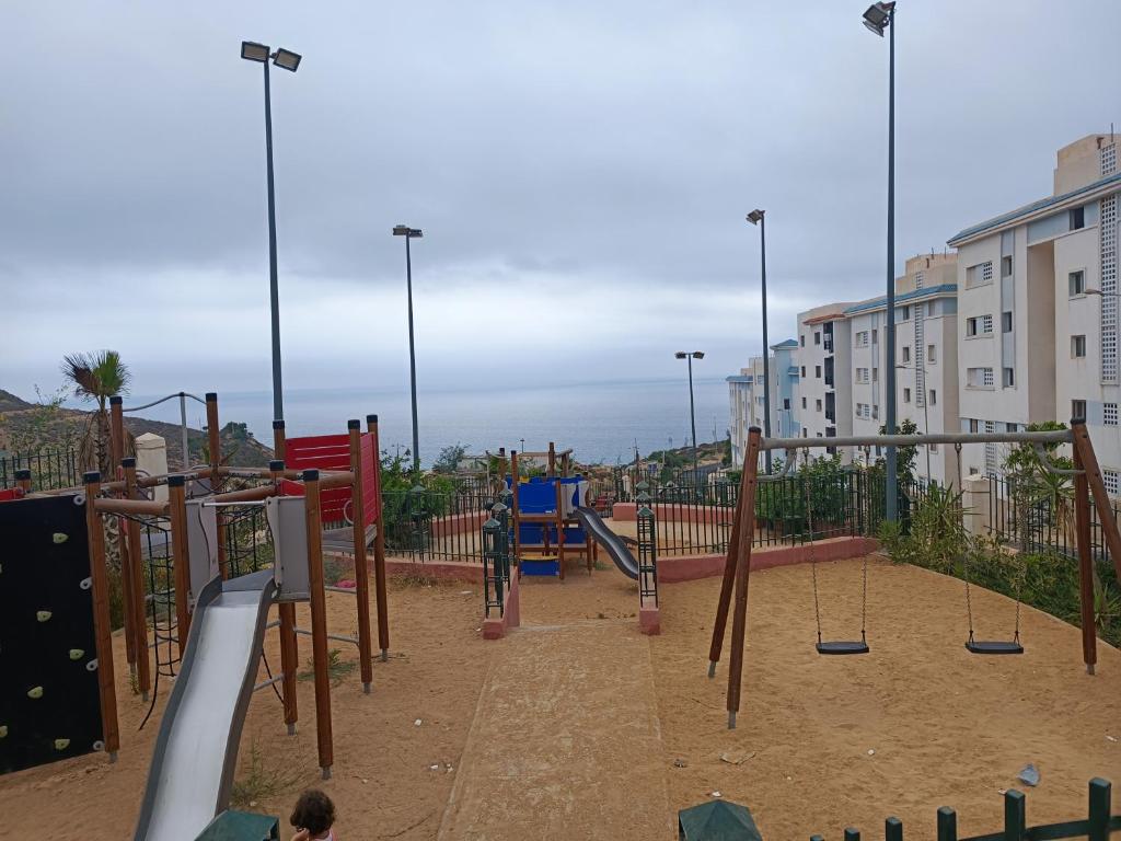 a playground with a slide and swings at الحسيمة in Tirhanimîne