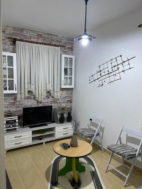 salon z telewizorem, stołem i krzesłami w obiekcie Dibra Home near City Center of Shkodra w Szkodrze