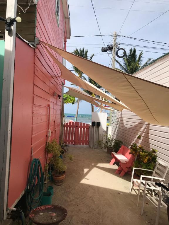 a patio with a red building and a white umbrella at Chila's Accommodations in Caye Caulker