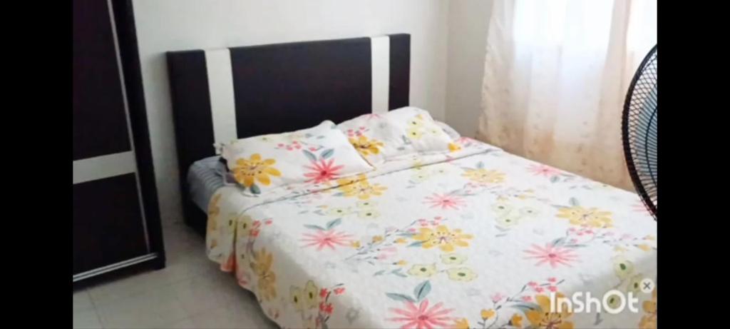 a bedroom with a bed with a floral bedspread at Homestay Kasturi Teluk Kalong Kemaman in Kijal