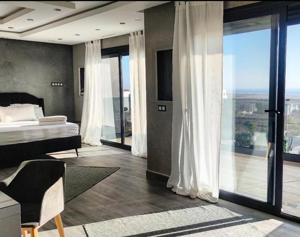 タンジェにあるVilla piscine sans vis à vis vue merのベッドルーム1室(ベッド1台付)、ガラスのスライドドアが備わります。
