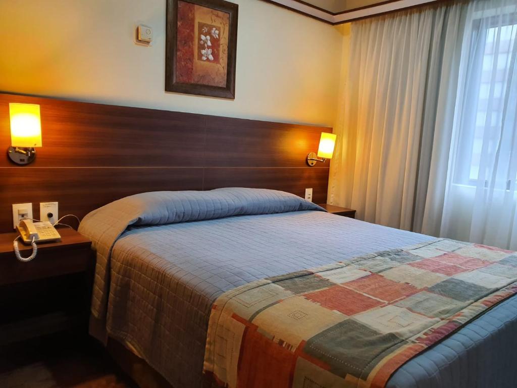 a bedroom with a bed and two lamps and a window at The Time Flat - Berrini - 200 metros do WTC in Sao Paulo