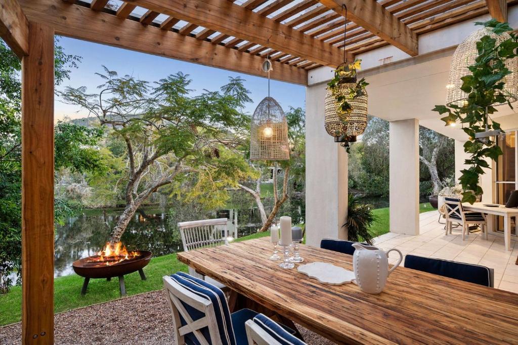 an outdoor dining area with a wooden table and a fireplace at Luxury Lakeside Villa in Yaroomba