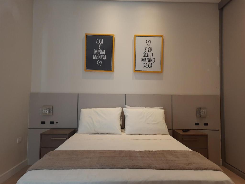 ein Bett in einem Schlafzimmer mit zwei Bildern an der Wand in der Unterkunft HillTop Serra da Mantiqueira in Sapucaí-Mirim