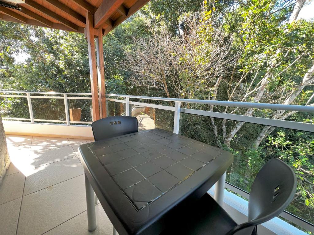a black table and chair on a porch with a view at Refúgio da Lagoinha - Centro de Bombinhas in Bombinhas
