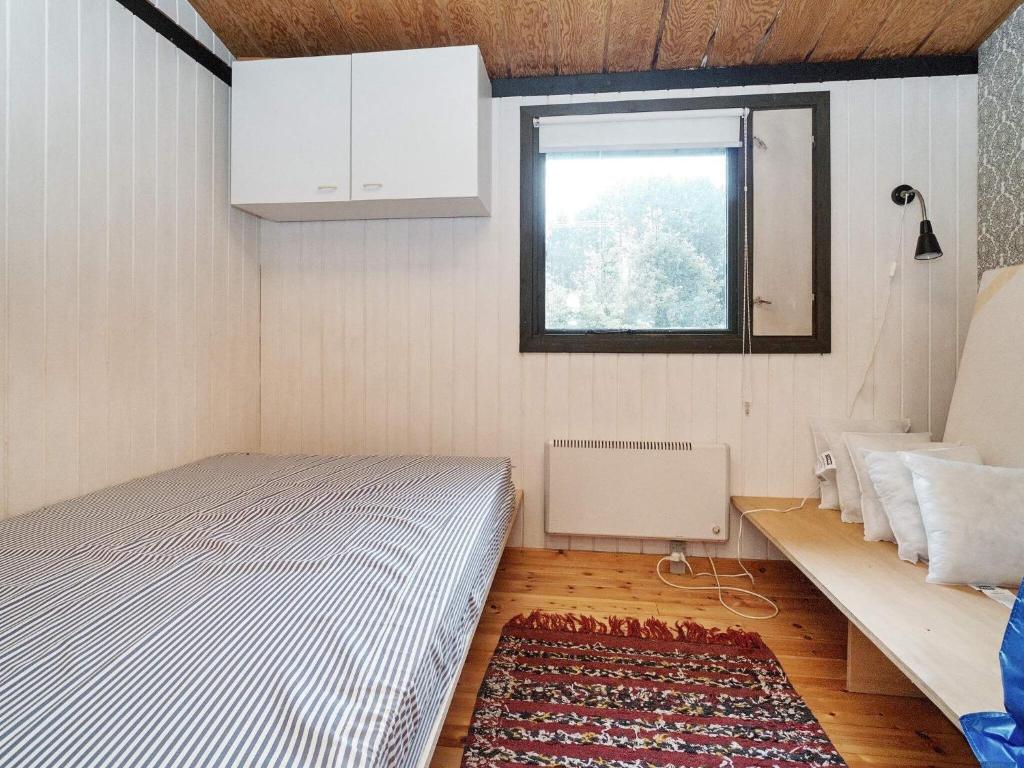 a small bedroom with a bed and a window at Holiday home Melby IX in Melby