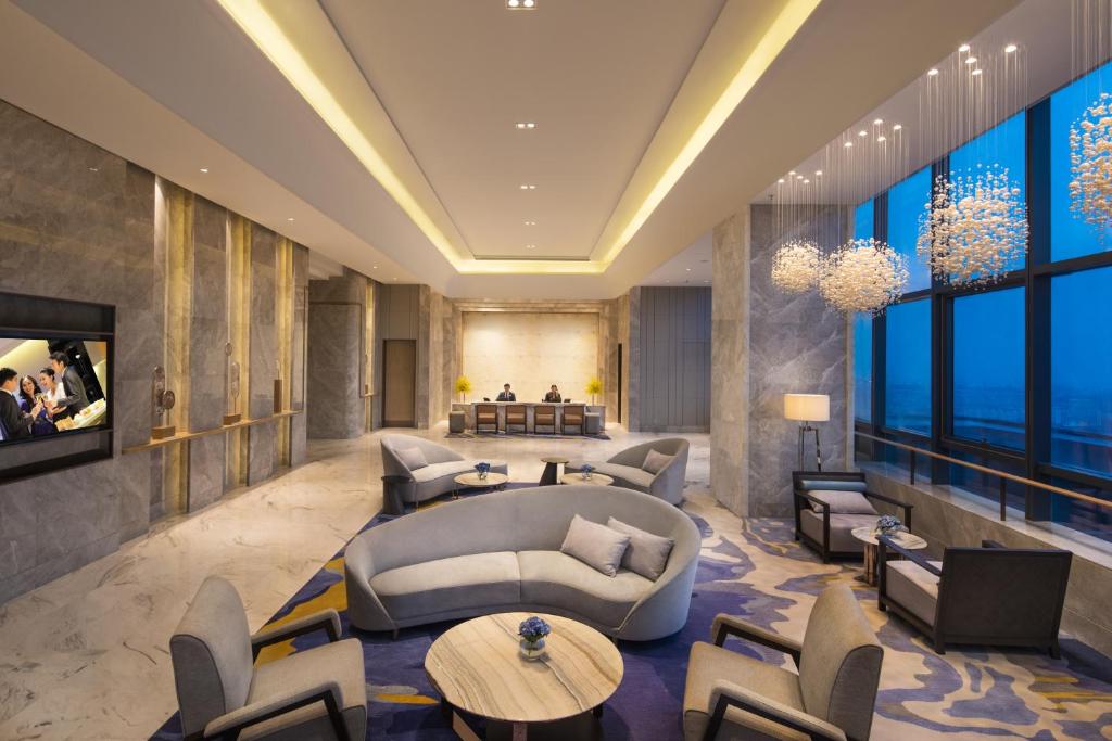 una hall con divano, tavoli e sedie di Ascott Harmony City Nantong a Nantong