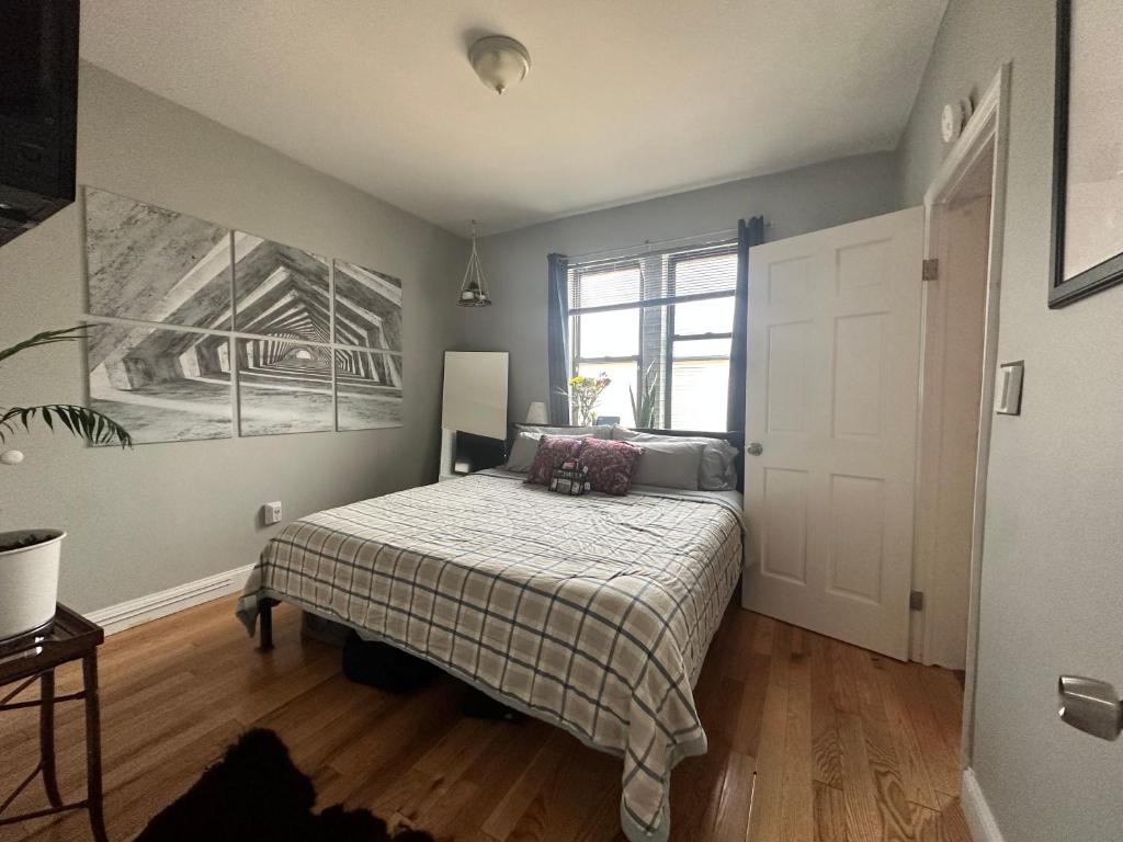 a bedroom with a bed with a blanket and a window at Queens Quarters in Steinway