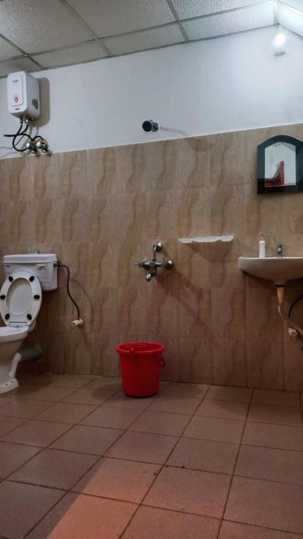 a bathroom with a toilet and a sink and a bucket at The Leisure Home Stay in Shādipur