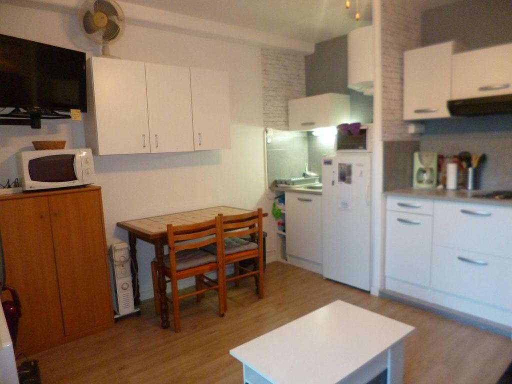 une cuisine avec des armoires blanches, une table et un micro-ondes dans l'établissement Studio 1 étoile proche du parc et de l'établissement Thermal, équipé pour 2 personnes - FR-1-571-58, à Balaruc-les-Bains
