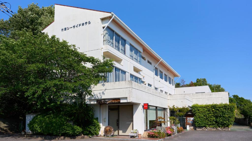 Un edificio bianco con un cane davanti di Tabist Setouchinoyado Takehara Seaside a Takekara