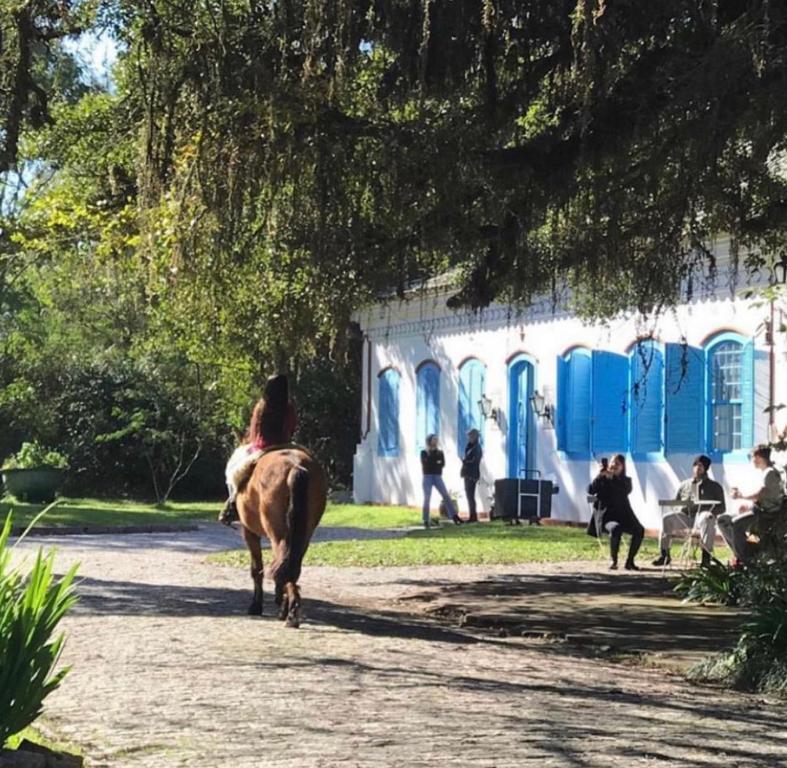 uma mulher montada num cavalo em frente a um edifício em Charqueada Santa Rita Pousada de Charme em Pelotas