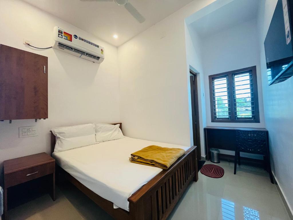 - une petite chambre avec un lit et une fenêtre dans l'établissement SRI BALAJI LODGING, à Tiruchchendūr