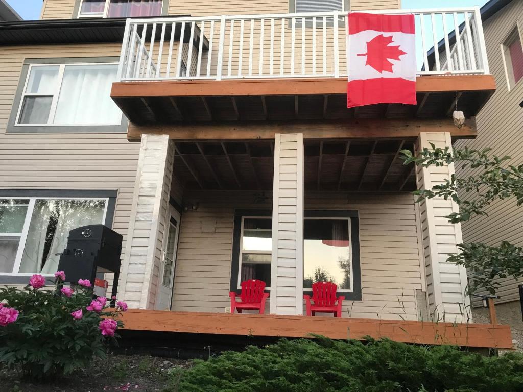 a house with a balcony with red chairs and a canadian flag at 民宿Ann's House in Calgary in Calgary