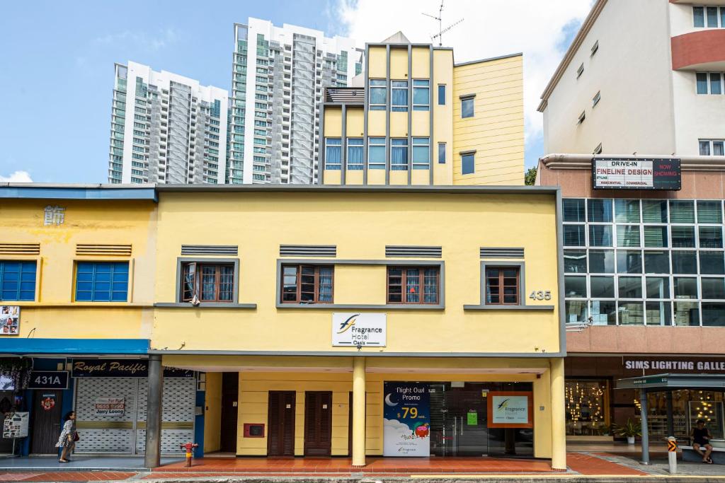 ein gelbes Gebäude vor hohen Gebäuden in der Unterkunft Fragrance Hotel - Oasis in Singapur