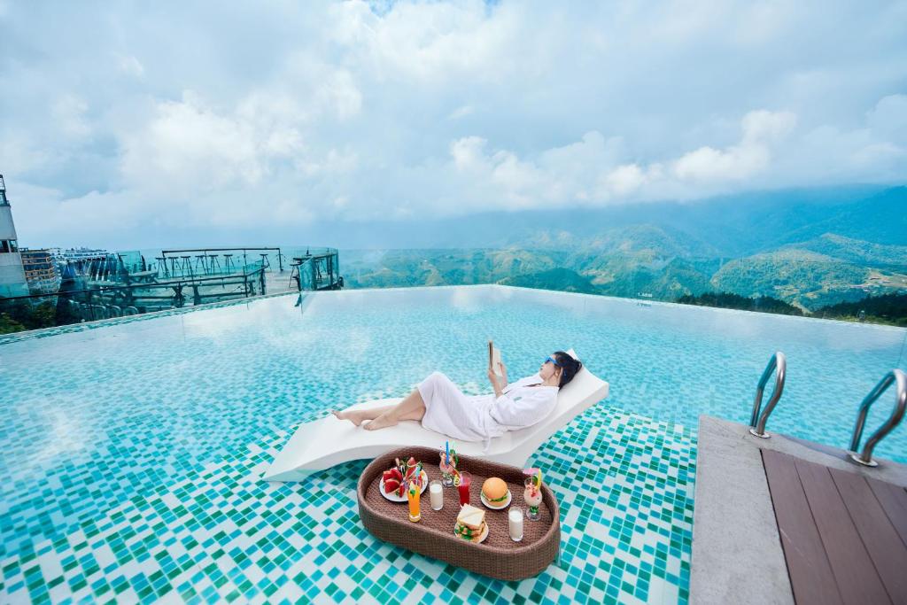 a woman laying on a chair on the edge of a pool at Bamboo Sapa Hotel in Sapa