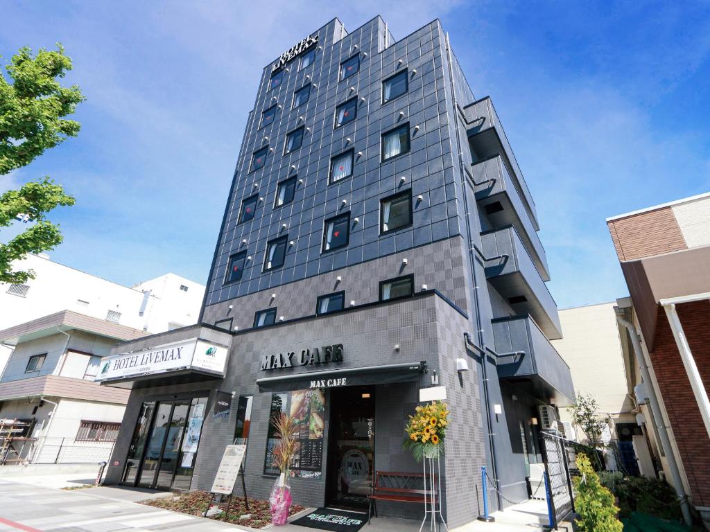a tall gray building on a city street at HOTEL LiVEMAX Sagamihara Ekimae in Sagamihara