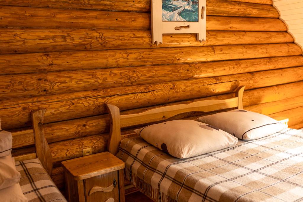 1 dormitorio con 1 cama en una cabaña de madera en Шепіт Карпат, en Synevyrsʼka Polyana