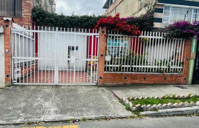 a white gate in front of a house with flowers at Habitación Agradable in Bogotá
