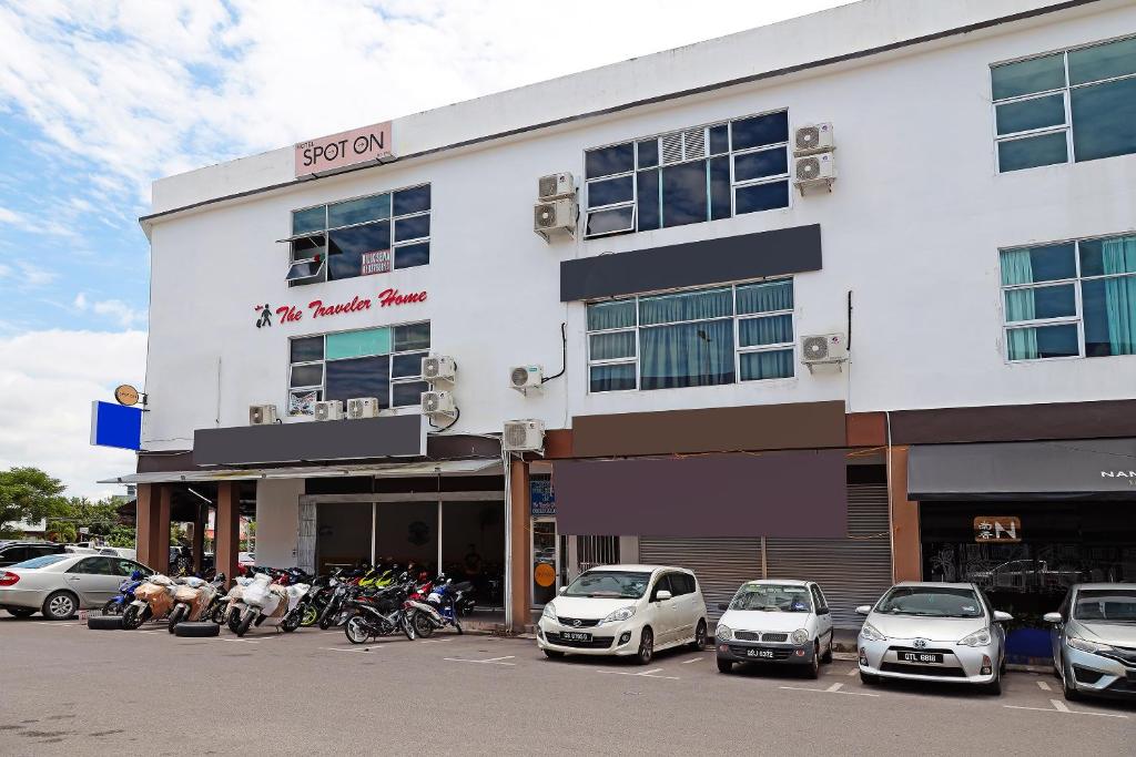 a white building with cars parked in front of it at SPOT ON 89805 The Traveler Home in Sibu