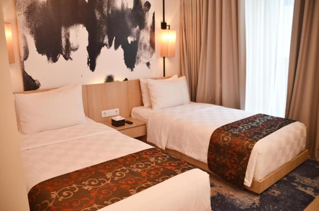 芝卡朗的住宿－Louis Kienne Hotel & Service Apartment，酒店客房设有两张床,墙上挂有绘画作品