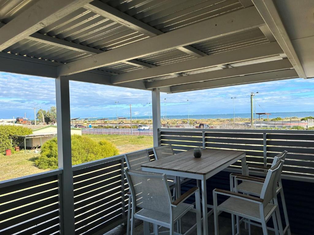 a table and chairs on a porch with a view of the ocean at Unit 54 Seafront Estate in Jurien Bay