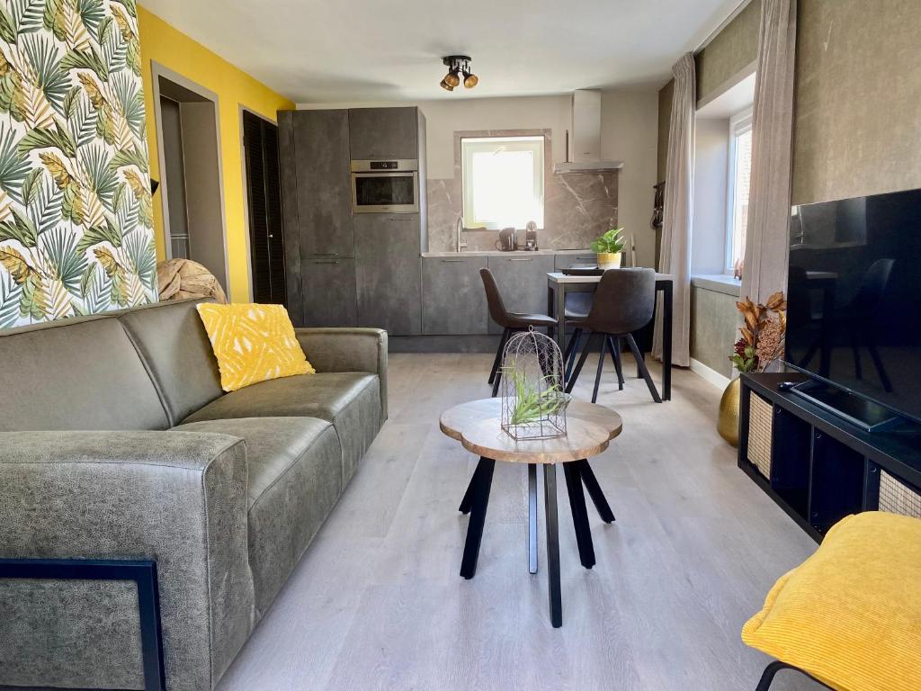een woonkamer met een bank en een tafel bij Glücklich am Meer Meerblick mit Wellnesszugang in Egmond aan Zee