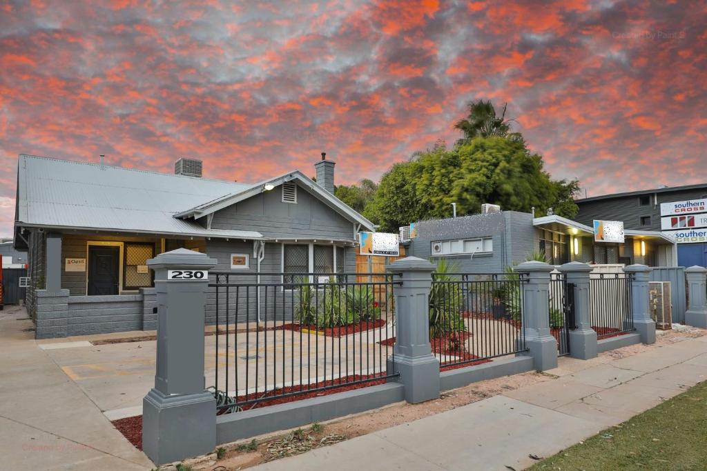 a fence in front of a house with a cloudy sky at Sunraysia Stays in Mildura