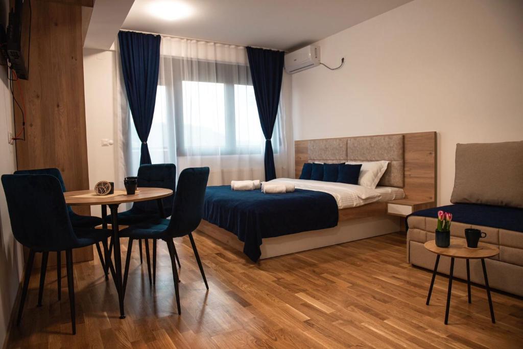 een slaapkamer met een bed en een tafel en stoelen bij Apartman Zlatanovic Jagodina in Jagodina